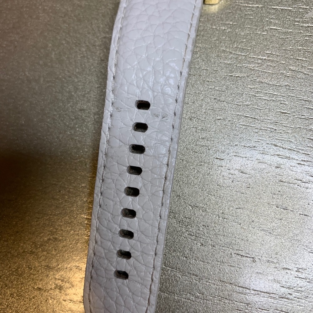 White leather belt with gold dial.